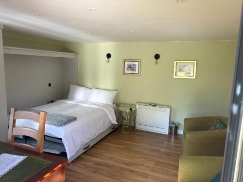 a bedroom with a bed and a chair and a desk at The Garden Studio in Wargrave