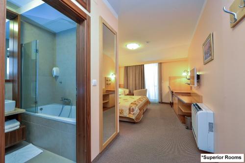 a hotel room with a bathroom with a bed and a tub at Hotel Joso in Sukošan
