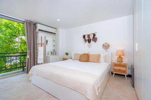 a white bedroom with a bed and a window at Kata Station Boutique Hotel, Kata Beach in Kata Beach
