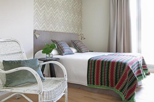 a bedroom with a bed with a blanket and a chair at Artesa Suites & Spa in Santo Tomé del Puerto