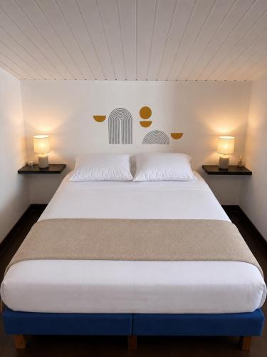 a bedroom with a large white bed with two lamps at La Canopé - T2 calme et central avec son jacuzzi in Rémire-Camp
