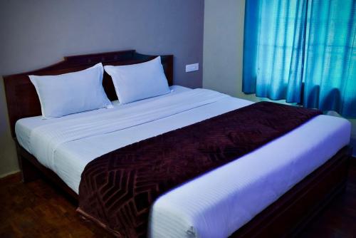 a bedroom with a large bed with white sheets at Shabeer's White Castle in Ooty