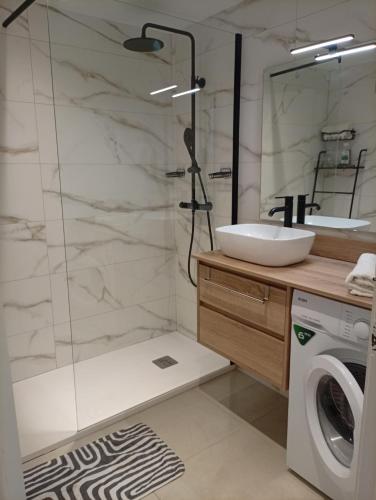 a bathroom with a shower and a sink and a washing machine at Appartement piscine Rosas in Roses