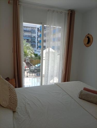 a bedroom with a bed and a window with a balcony at Appartement piscine Rosas in Roses