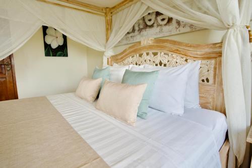 a bedroom with a large bed with white and blue pillows at Poinciana Resort in Tejakula