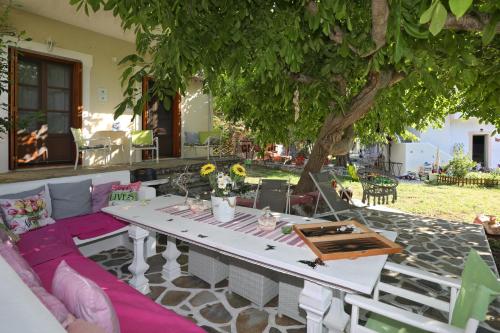 a table and chairs on a patio under a tree at Sklavos Studios skopelos in Neo Klima