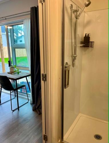 a shower with a glass door in a room with a table at Oasis in onerahi in Whangarei