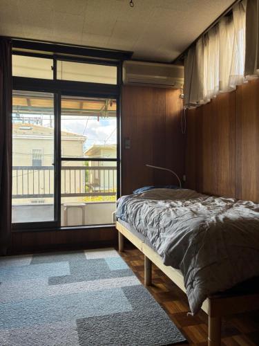 a bedroom with a bed and a large window at スペースigusa専用寝室2室に2名様3泊よりマンスリー割引がおすすめ in Tokyo