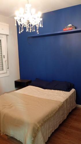a blue bedroom with a bed and a chandelier at Apartamento central bem localizado in Pelotas