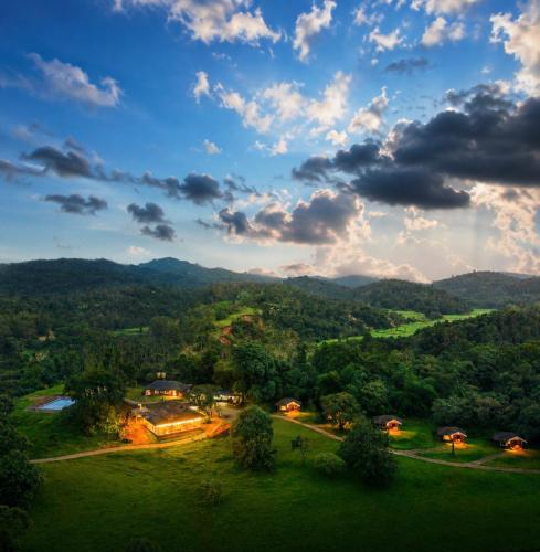 a view of a green field with mountains in the background at Sterling Kadumane Hills Sakleshpur in Sakleshpur