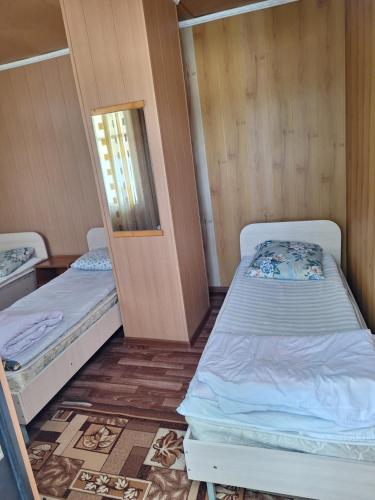 two beds in a small room with a mirror at Сакура in Cholpon-Ata
