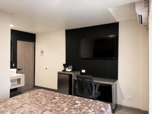 a hotel room with a desk and a television on the wall at Sereno Business Inn in Ensenada