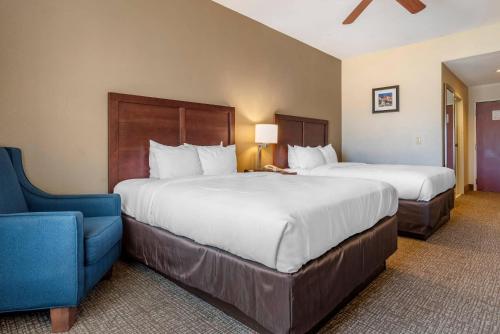 a hotel room with two beds and a blue chair at Comfort Inn & Suites Clinton - Jackson West in Clinton
