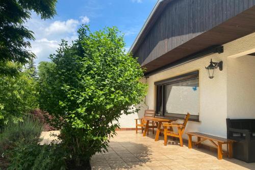 a patio with wooden tables and chairs and a tree at Gästehaus Bergstraße Hammermühle in Bad Düben