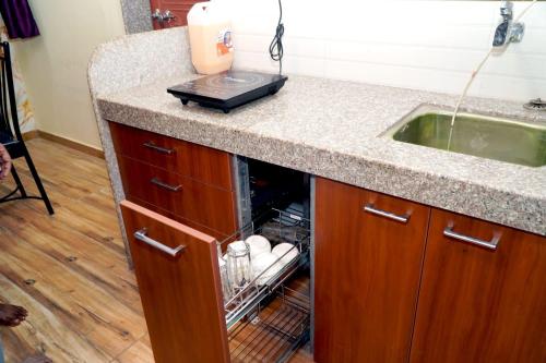 a kitchen counter with an open dishwasher next to a sink at Sitara Homestay in Ratnagiri
