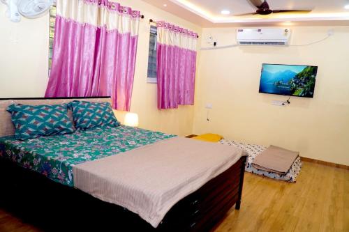 a bedroom with a bed and a tv on the wall at Sitara Homestay in Ratnagiri