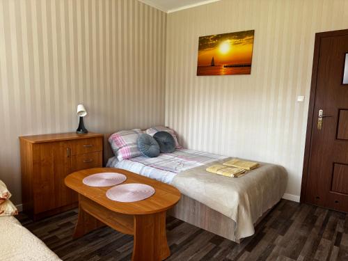 a small bedroom with a bed and a table at Pokoje i Domki Nadmorskie - Bajkowa Mierzeja in Stegna