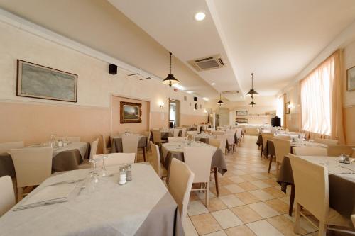 a dining room with white tables and chairs at Hotel Carol in Cesenatico