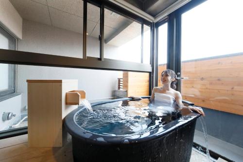 a woman in a bath tub in a room at ゆるり奥日光withDOGS in Nikko