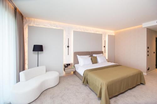 a bedroom with a large bed and a white chair at Ollie's by the sea in Donja Lastva