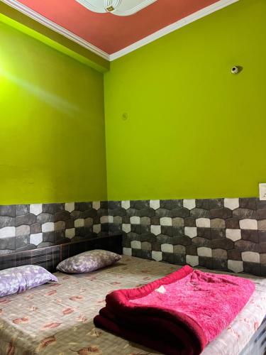 a green room with a bed with a pink blanket at Hotel Lotus in Banbāsa