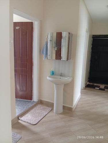a bathroom with a white sink and a mirror at EMIC Suites in Nyahururu