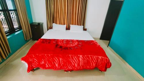 a bed with a red bedspread on it in a room at Sivadurga in Varkala