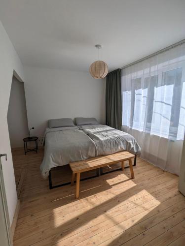 ein Schlafzimmer mit einem Bett und einer Bank vor einem Fenster in der Unterkunft L'Eauberge in La-Roche-en-Ardenne