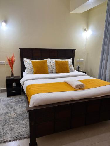 a bedroom with a large bed with yellow pillows at Nesty Homes in Gitura