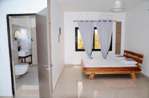 a white bathroom with a bed and a toilet at VILLA ÉKÉ Baguida plage in Baguida