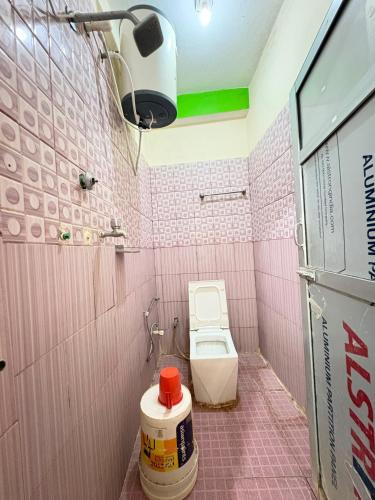 Ein rosa gefliestes Badezimmer mit Toilette und Dusche. in der Unterkunft Kasturi Hotel in Champapur