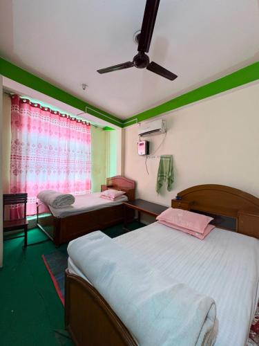 ein Schlafzimmer mit zwei Betten und einem Deckenventilator in der Unterkunft Kasturi Hotel in Champapur