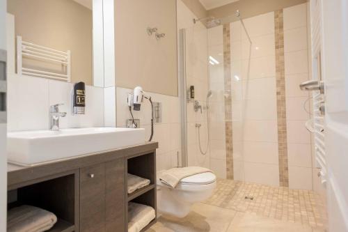 ein Bad mit einem WC, einem Waschbecken und einer Dusche in der Unterkunft Ostseehotel Warnemünde in Warnemünde