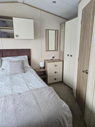 a bedroom with a bed and a dresser and a mirror at Bayview at Pengarreg in Llanrhystyd