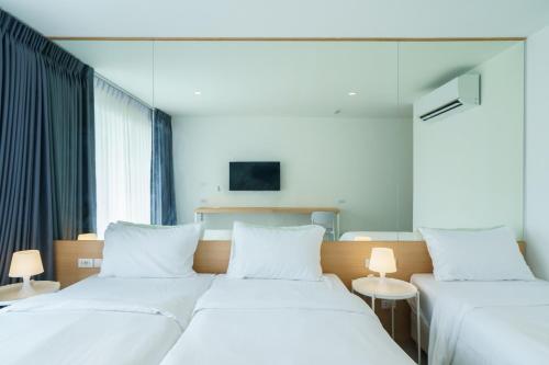two beds in a hotel room with white pillows at Lis Hotel Chiangmai in Chiang Mai