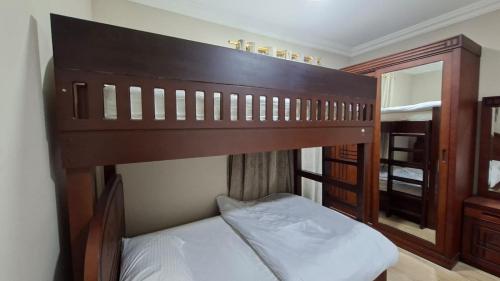 a bedroom with a wooden bunk bed with white sheets at حياة النعيم in Salalah
