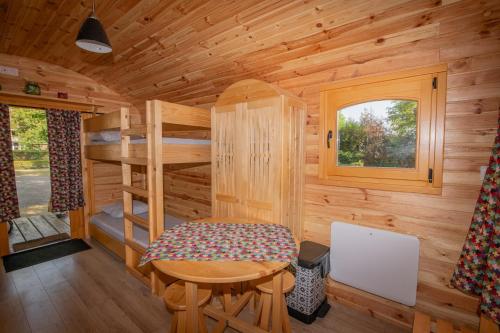 a wooden cabin with a small table and a window at Camping Onlycamp du Rouergue in Villefranche-de-Rouergue