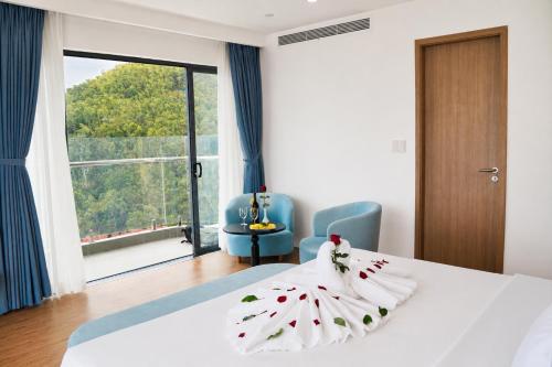 a bedroom with a white bed and a large window at The Golden Crest Hotel Quy Nhon in Quy Nhon