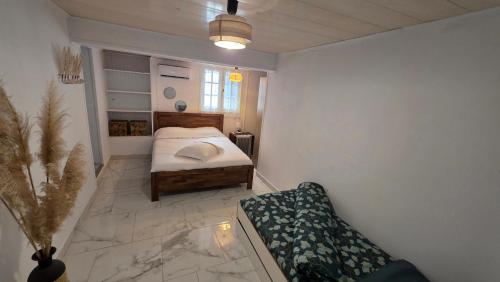 a small bedroom with a bed and a couch at Entre Mer et Volcan ,piscine chauffée au tampon in Bel Air