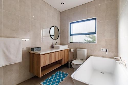 a bathroom with a tub and a sink and a toilet at Braham Lodge - The Octave 5 in Johannesburg
