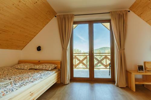 a bedroom with a bed and a large window at Sokoli Zakątek - domki w Bieszczadach in Bukowiec