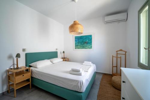 a white bedroom with a bed and a window at Sea Houses SERIFOS in Rámos