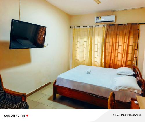 a bedroom with a bed and a flat screen tv at 0YE' Hotel in Ashalebotwe