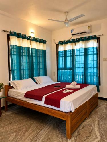 a bedroom with a large bed with blue curtains at La Muthu Beach Stay in Pondicherry
