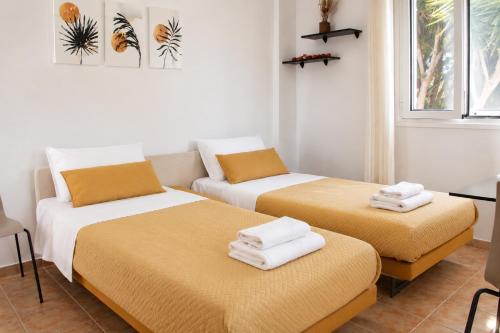 two beds in a room with towels on them at Lagouvardos Beach Apartments in Marathopoli