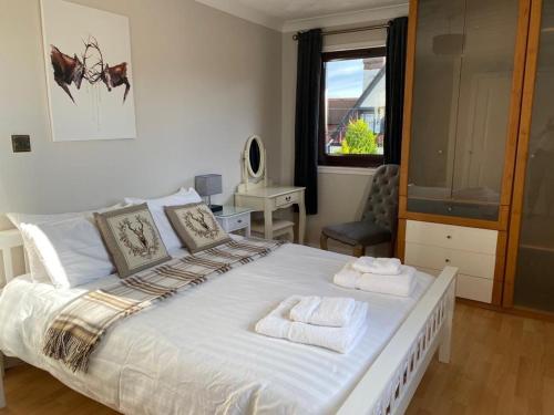 a bedroom with a large bed with towels on it at Lomond Villa in Balloch