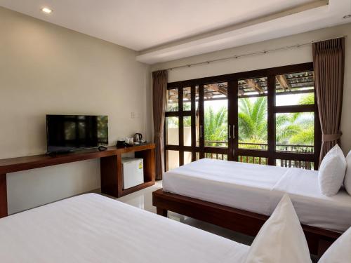 a hotel room with two beds and a television at Sunset Beach Villas in Haad Rin