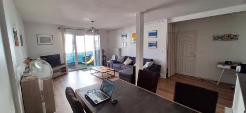 a living room with a couch and a laptop on a table at Le vitrail d'Arcachon - Appt Spacieux Terrasse Ménage draps inclus in Arcachon