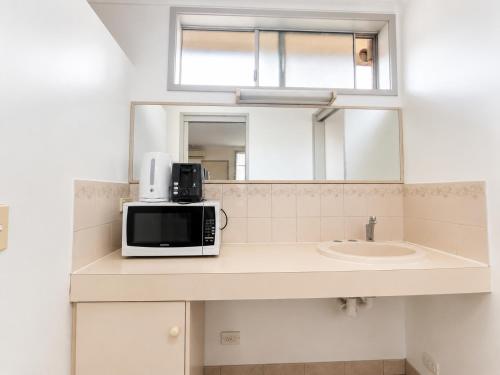 a microwave sitting on a counter next to a sink at Beaconsfield Lodge Motel in Beaconsfield