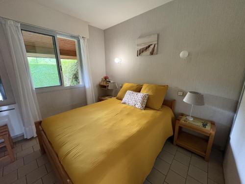 a bedroom with a yellow bed with a window at Albizias 3 in Eugénie-les-Bains